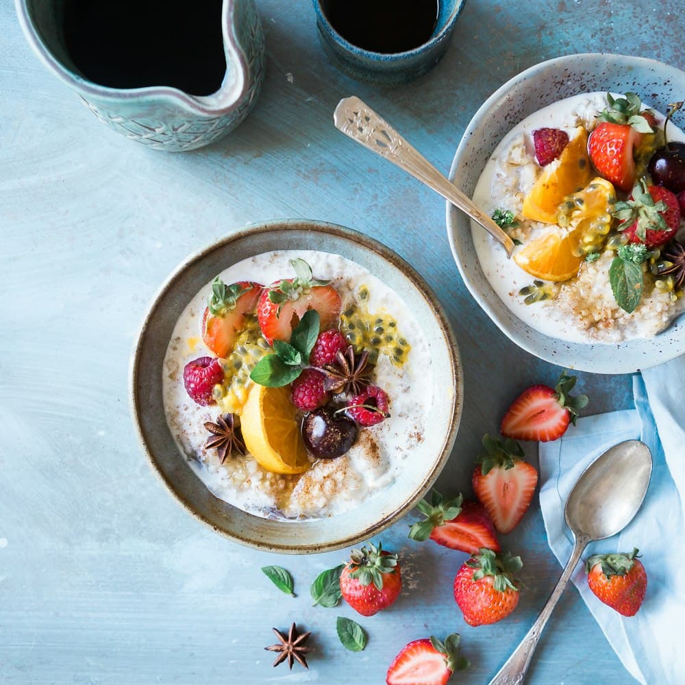 Bowls of oatmeal topped with fresh berries and fruit