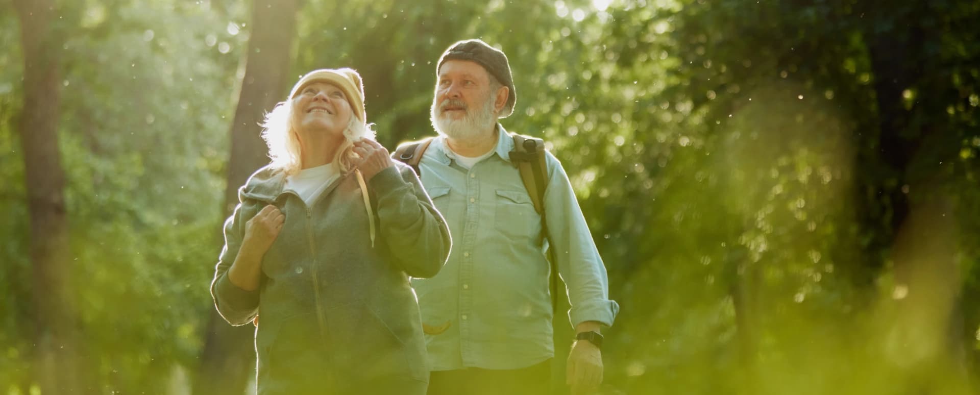 An active older couple hiking outdoors on a bright day